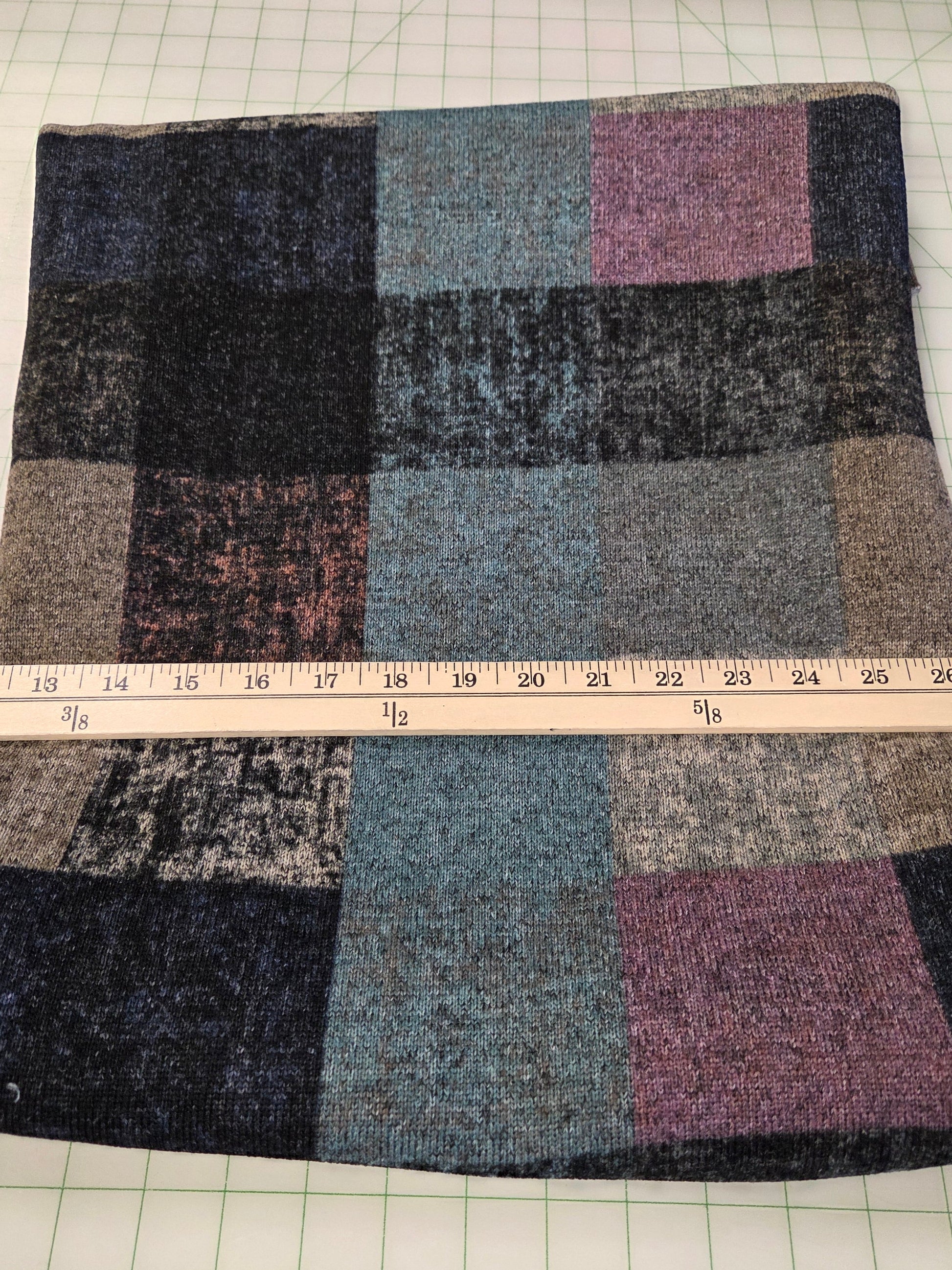 Checkered fabric sample with a ruler for scale on a grid background. apparel fleece knit