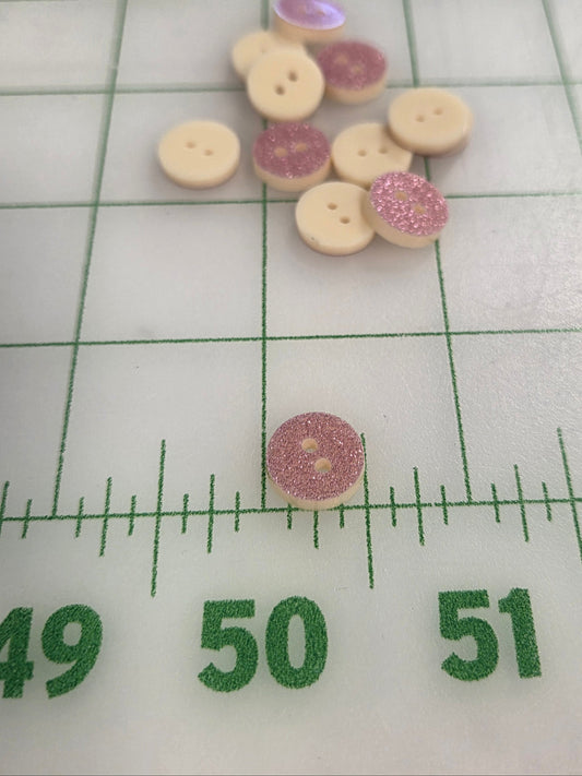 Buttons with pink glittery centers on a white background with green measurement scale