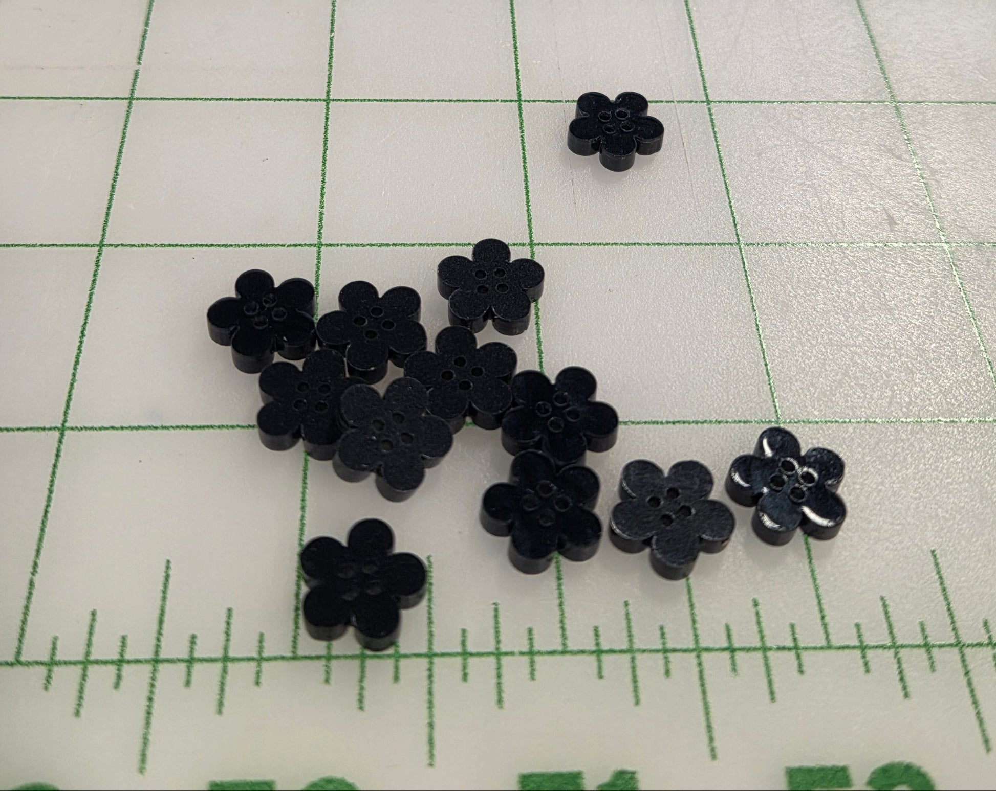 Black flower-shaped objects on a grid background with measurement scale