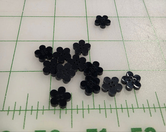 Black flower-shaped objects on a grid background with measurement scale