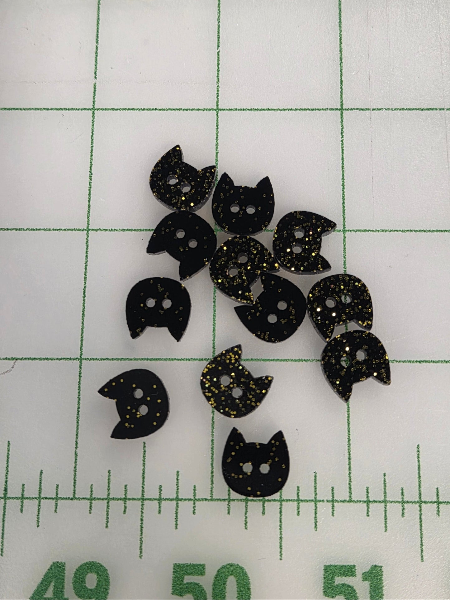 Black cat-shaped objects on a white surface with green grid lines and measurements.