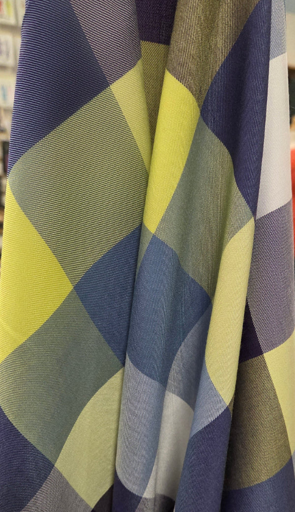 Folded fabric with a blue and green checkered pattern in an indoor setting.
