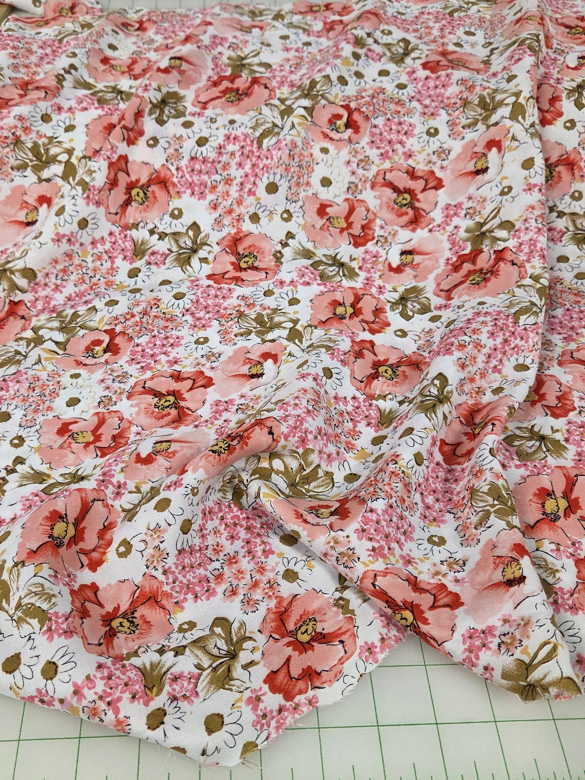 Floral fabric with pink and green flowers on a white background, measured with a ruler.