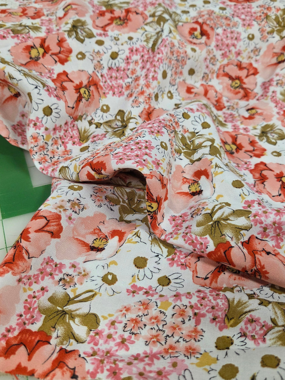Floral fabric with pink and green flowers on a cutting mat. LA Finch Fabrics. Floral woven for dressmaking. Southern California