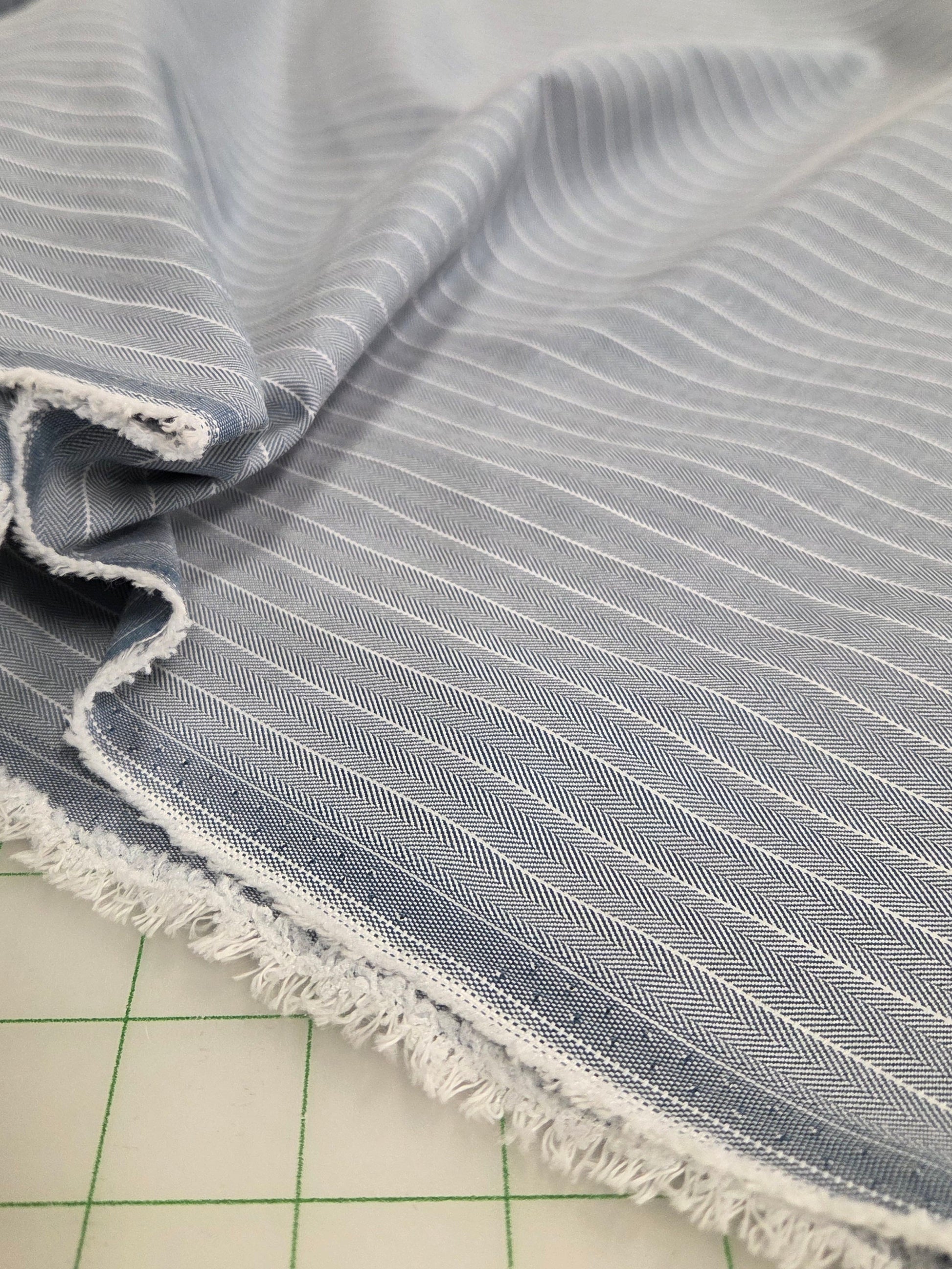 Close-up of textured fabric with frayed edge on a grid background