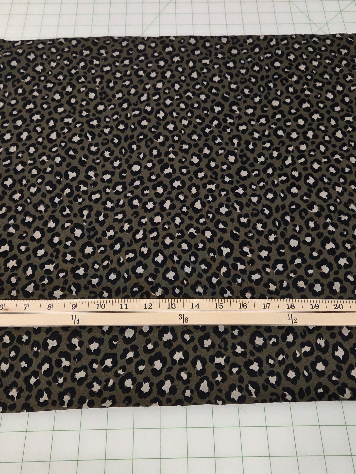 Fabric with a pattern on a cutting mat with a ruler and scissors.