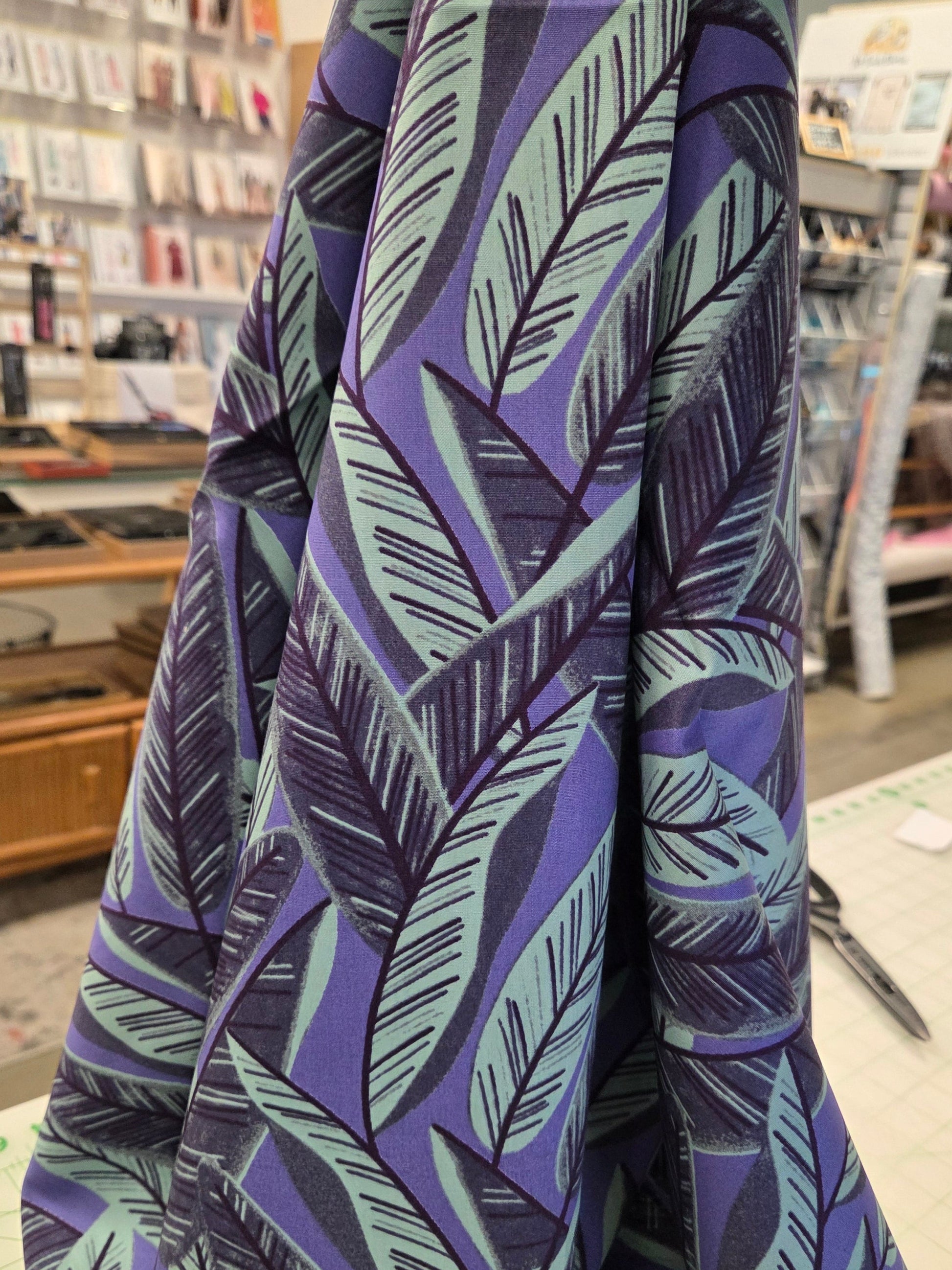 Folded fabric with purple and green leaf pattern on a cutting mat