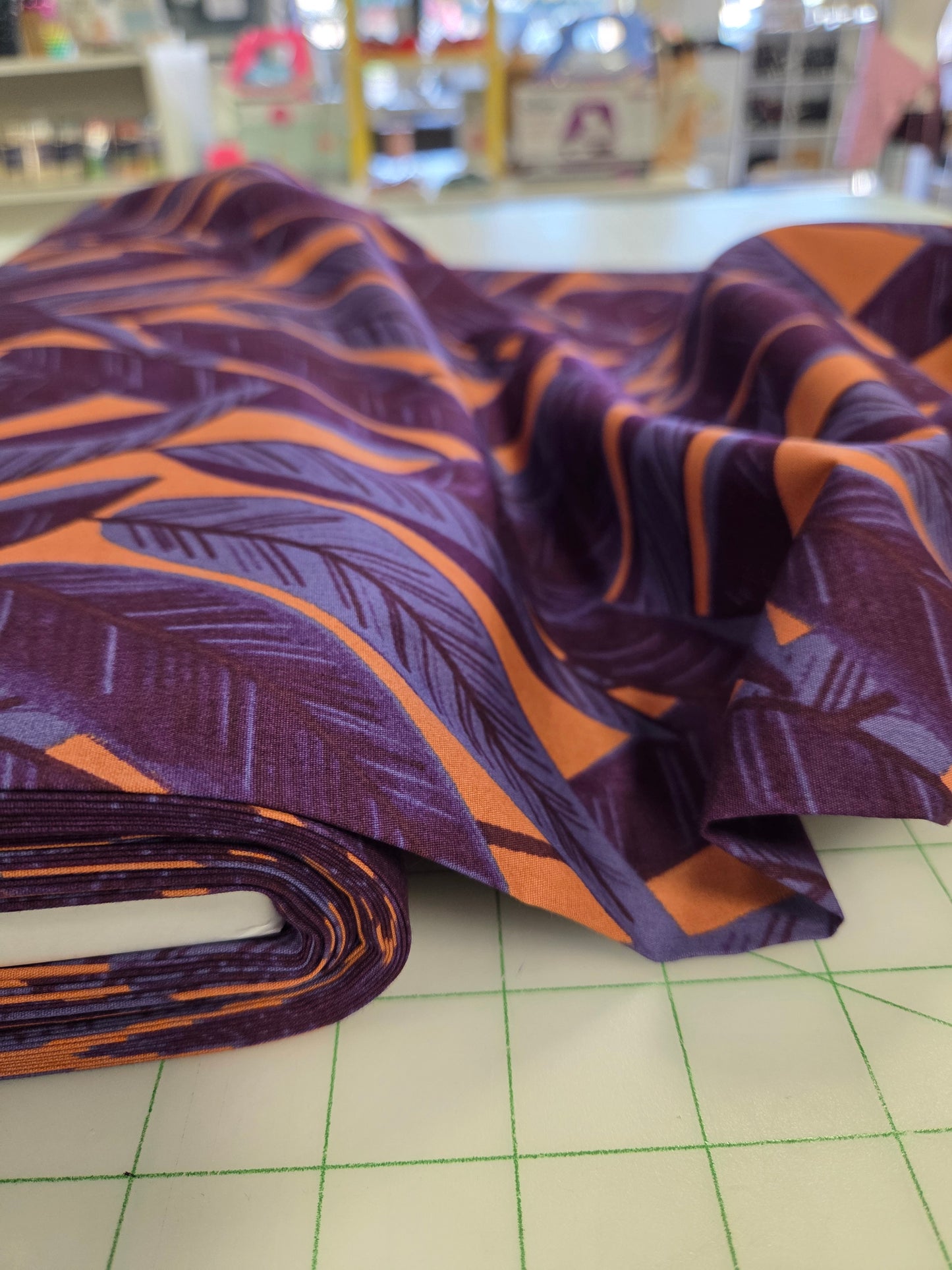 Roll of purple and orange patterned fabric leaning against a grid surface.