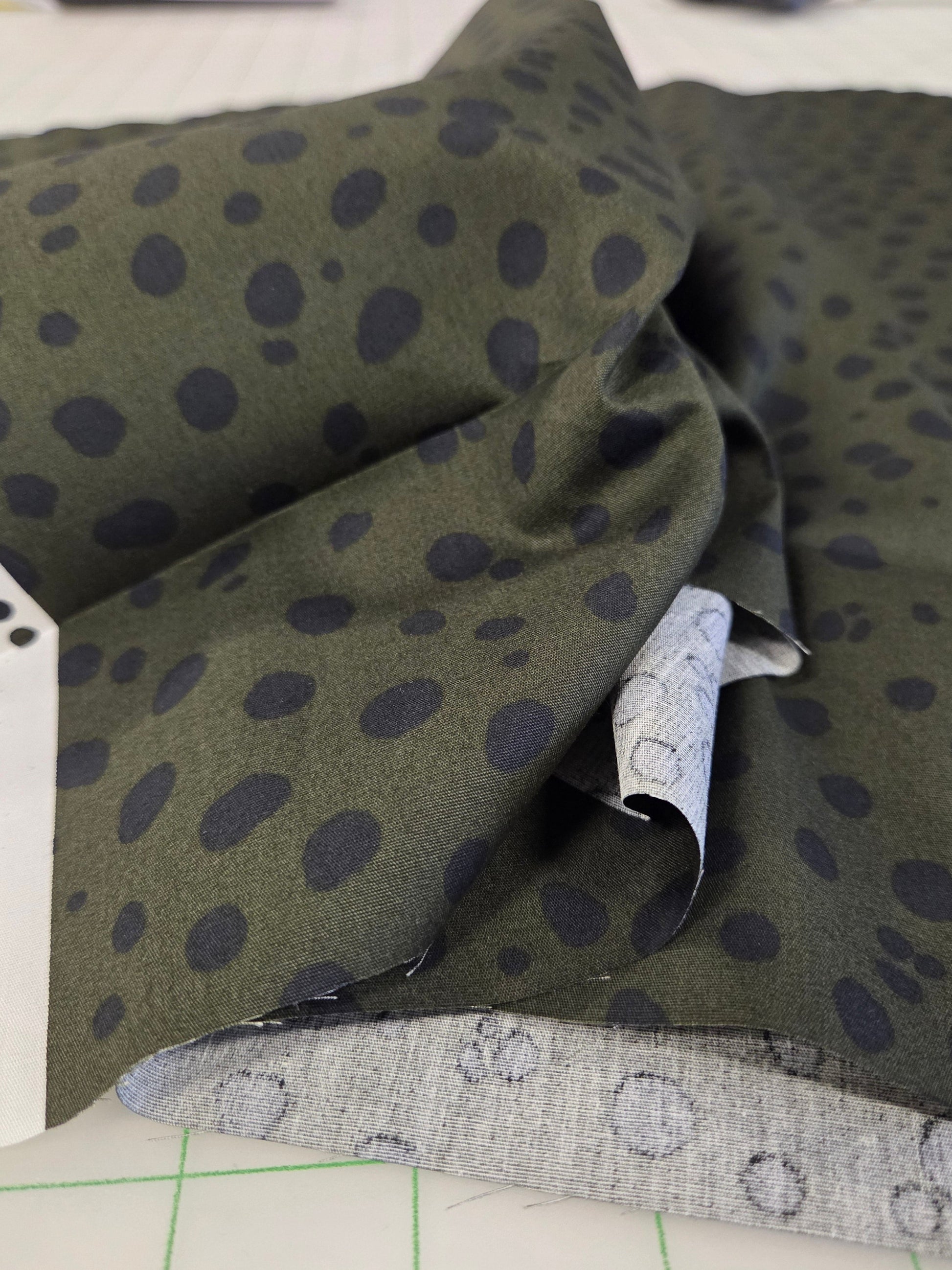 Green fabric with black polka dots on a white surface