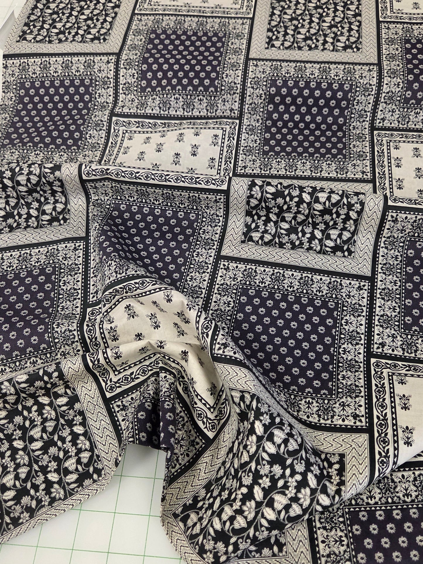 Patchwork fabric with black and white patterns on a cutting mat. hokkoh japan import bandana
