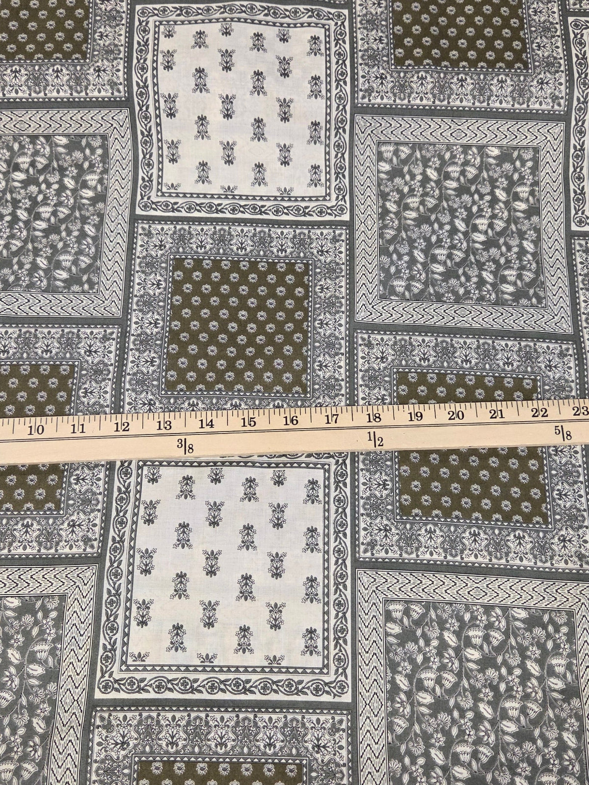 Patchwork fabric with a measuring tape for scale on a checkered surface