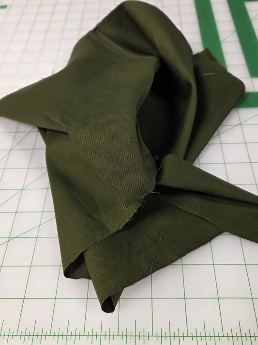 Folded green fabric on a cutting mat with measurements. Japan fabric oxford solid or garment and bag making