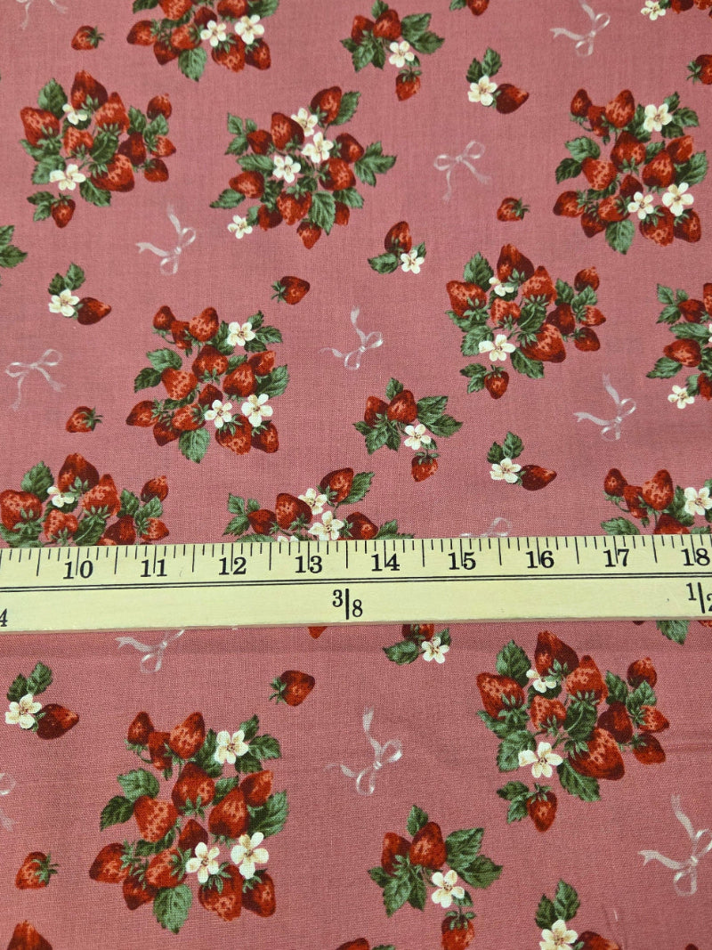 Fabric with strawberry pattern and a ruler for scale on a pink background