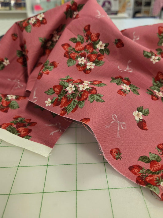 Fabric with strawberry pattern on a cutting mat in a store setting. UN No japan fabric 