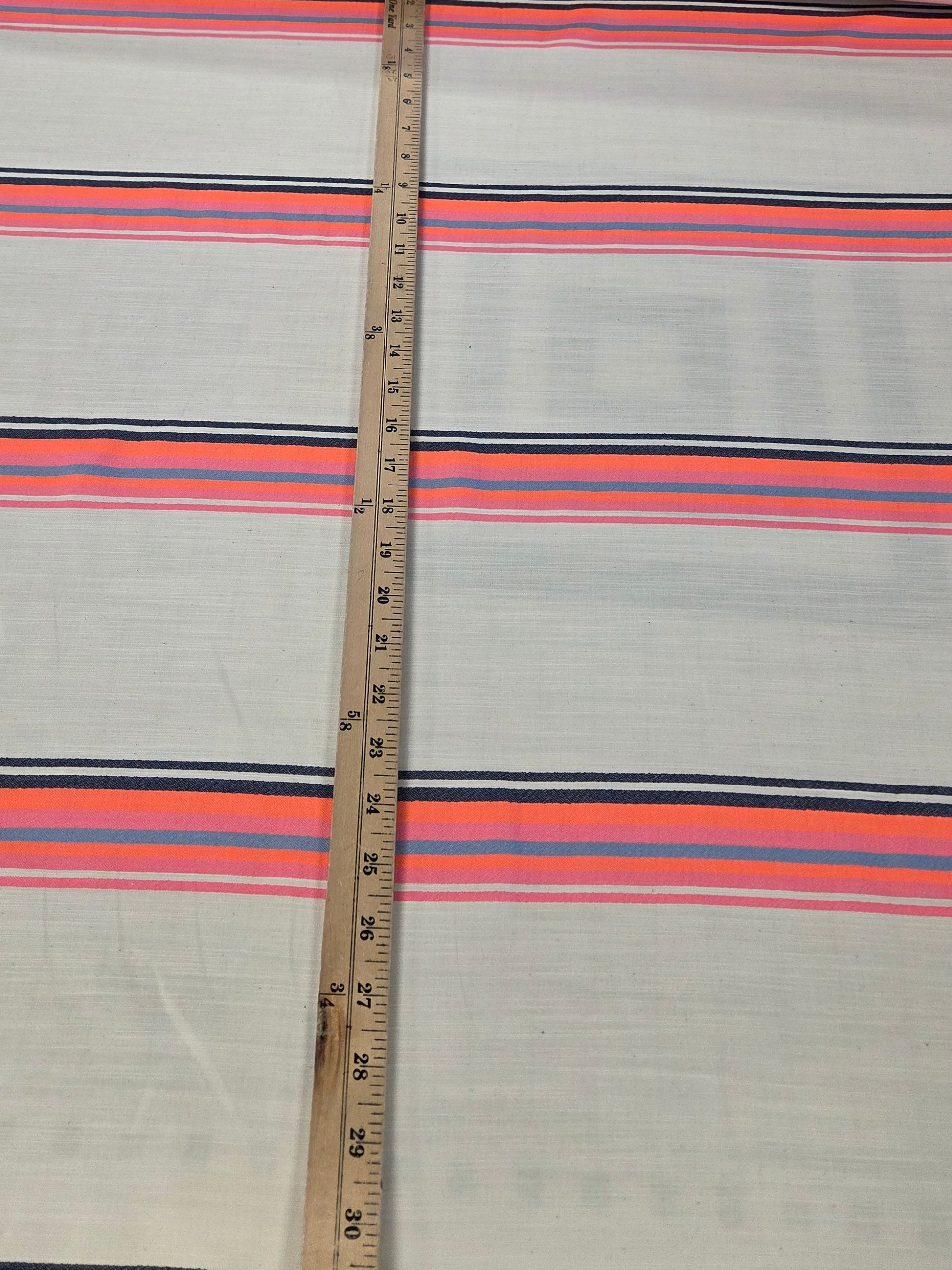 Striped fabric with a measuring tape laid across it, on a neutral background