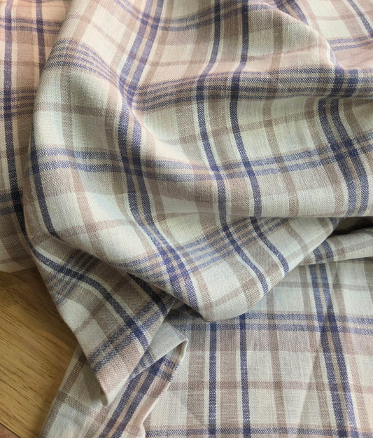 Plaid fabric with brown and blue pattern on a wooden surface. Designer deadstock fabric by the yard. 