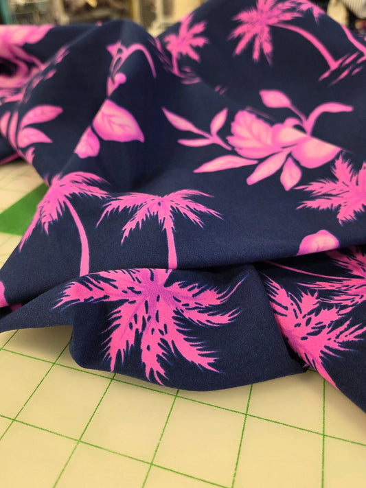 Navy blue fabric with pink floral pattern on a cutting mat