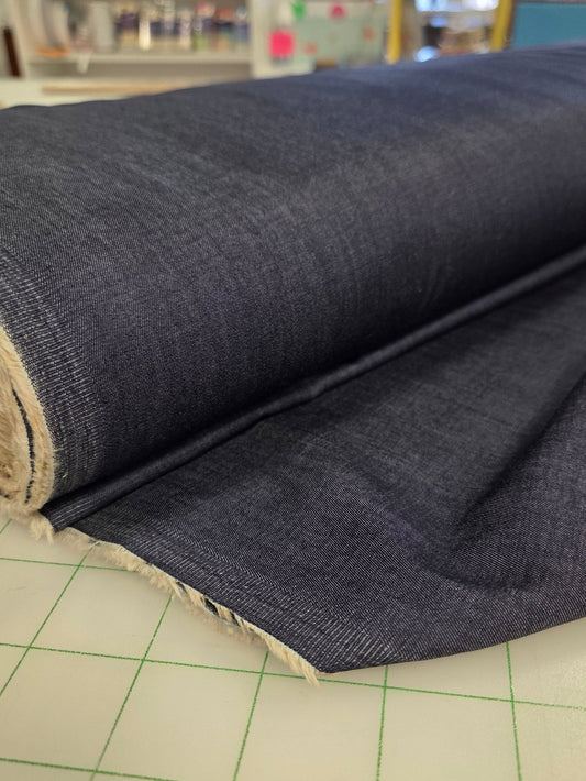 Roll of dark fabric on a cutting mat with a blurred store background