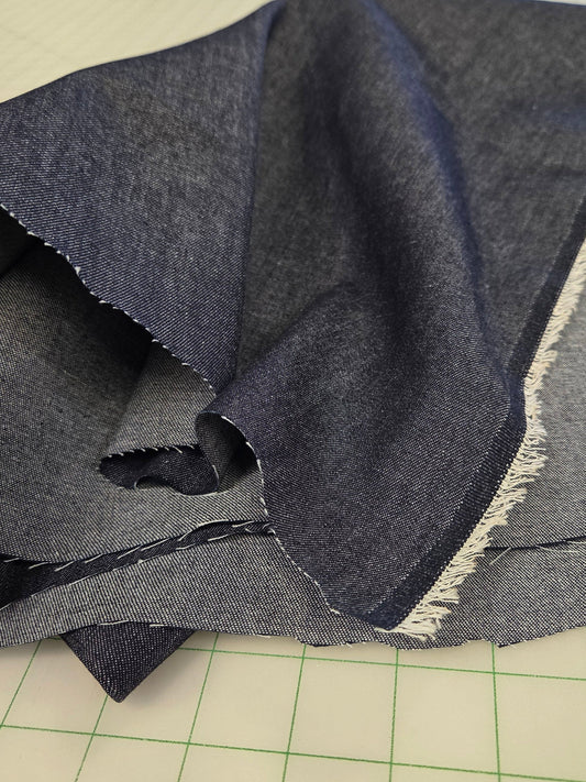 denim dark shirting weight blue fabric with a fringe edge on a cutting mat