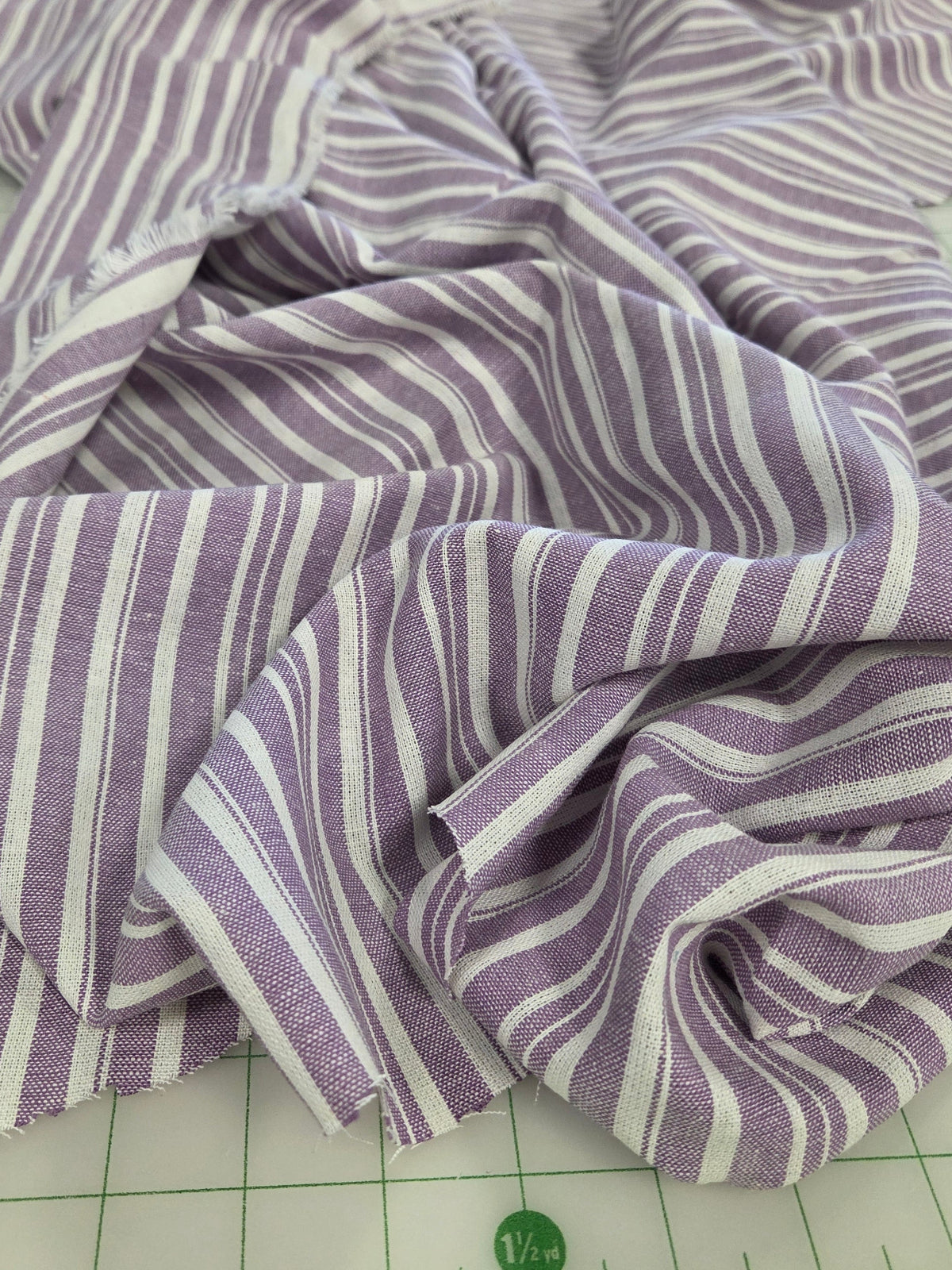 Purple and white striped fabric draped on a green cutting mat with measurement markings.