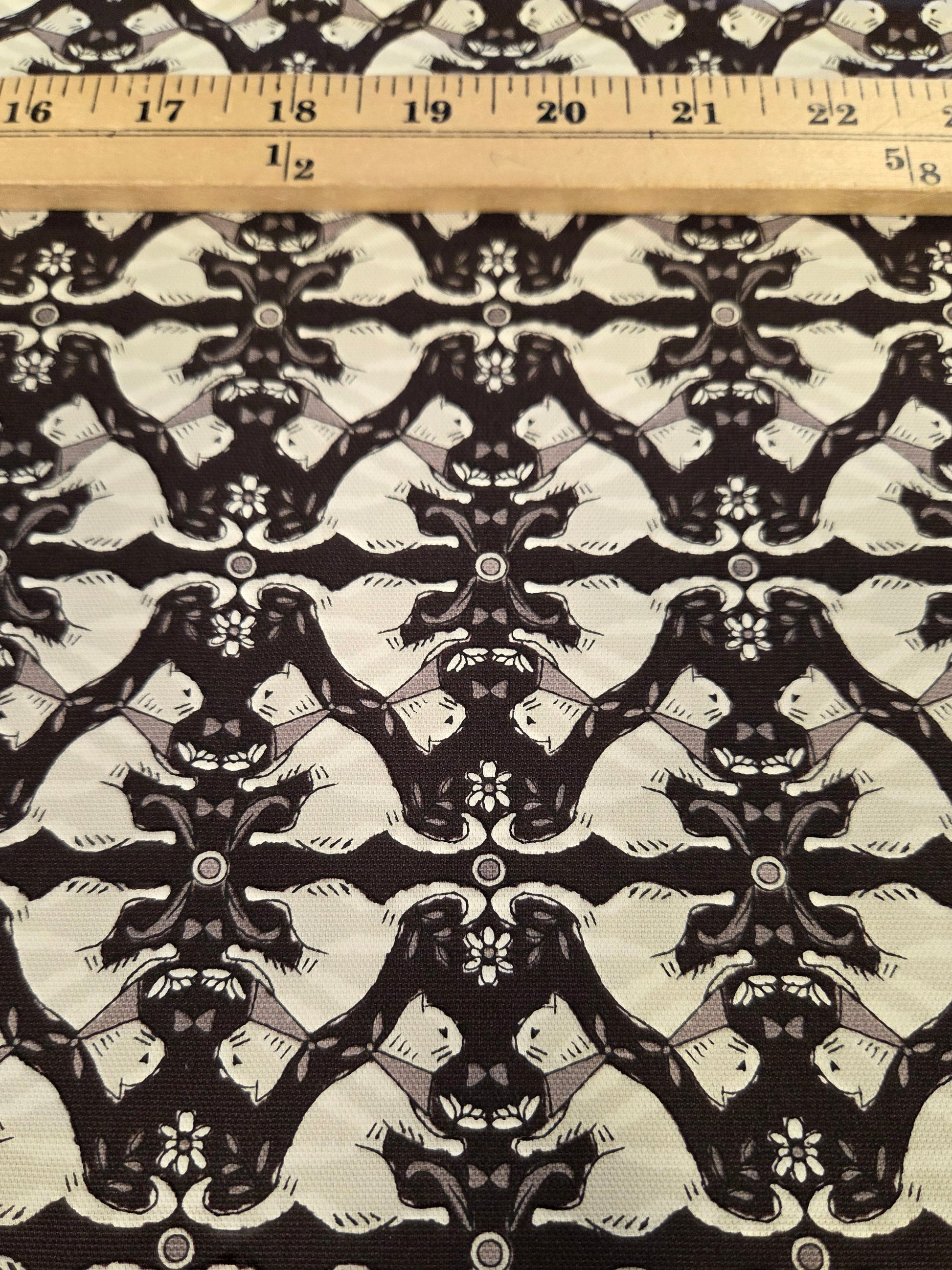 Black and off-white damask patterned fabric with a wooden ruler on the left side for scale.