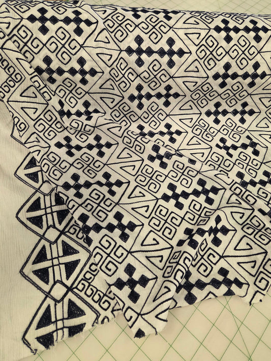 blue and white patterned fabric draped over a cutting mat, featuring a geometric tribal-style print with triangles, diamonds, and zigzags.