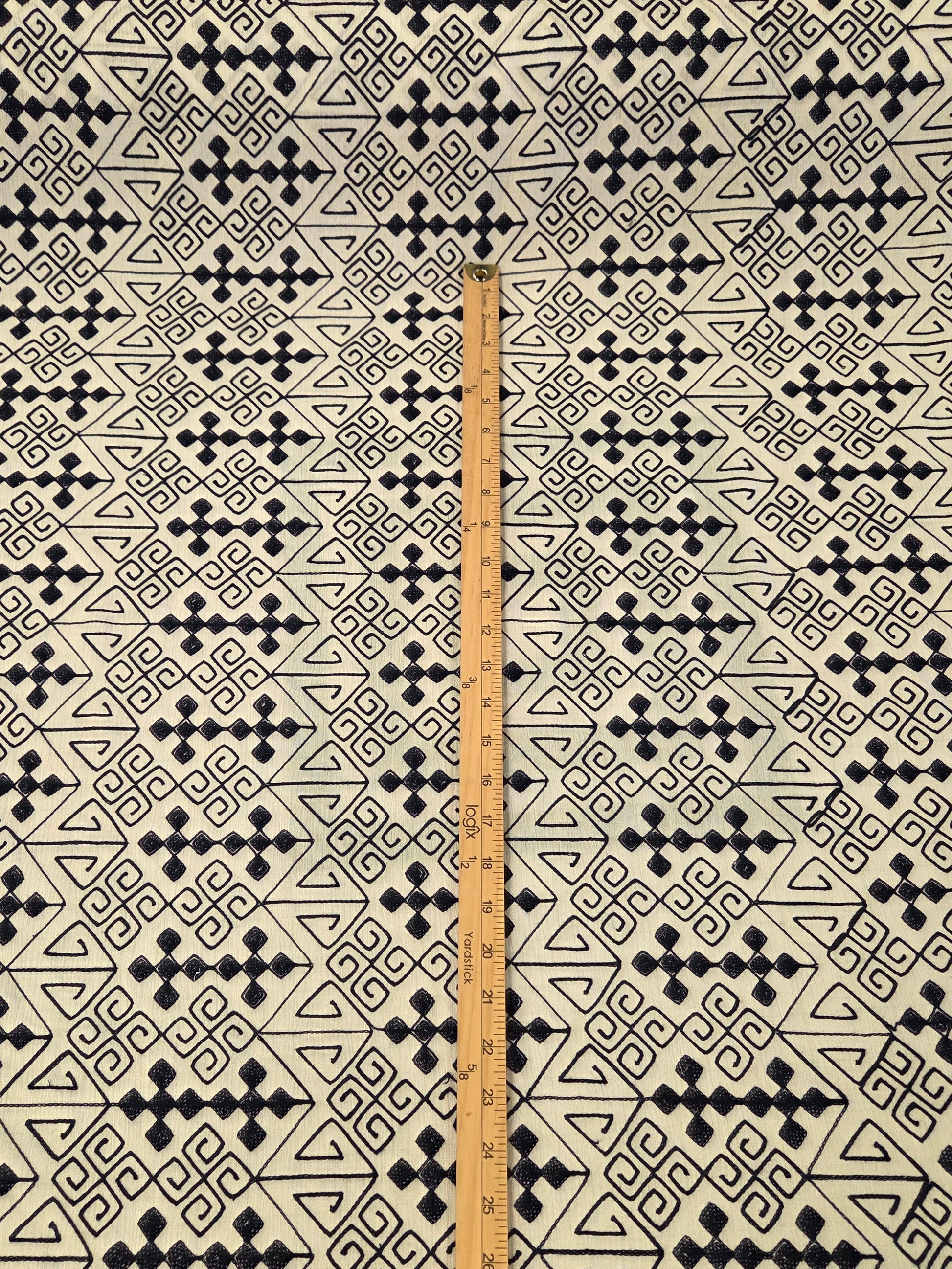 navy and white patterned fabric laid flat with a wooden ruler standing vertically in the center for scale.