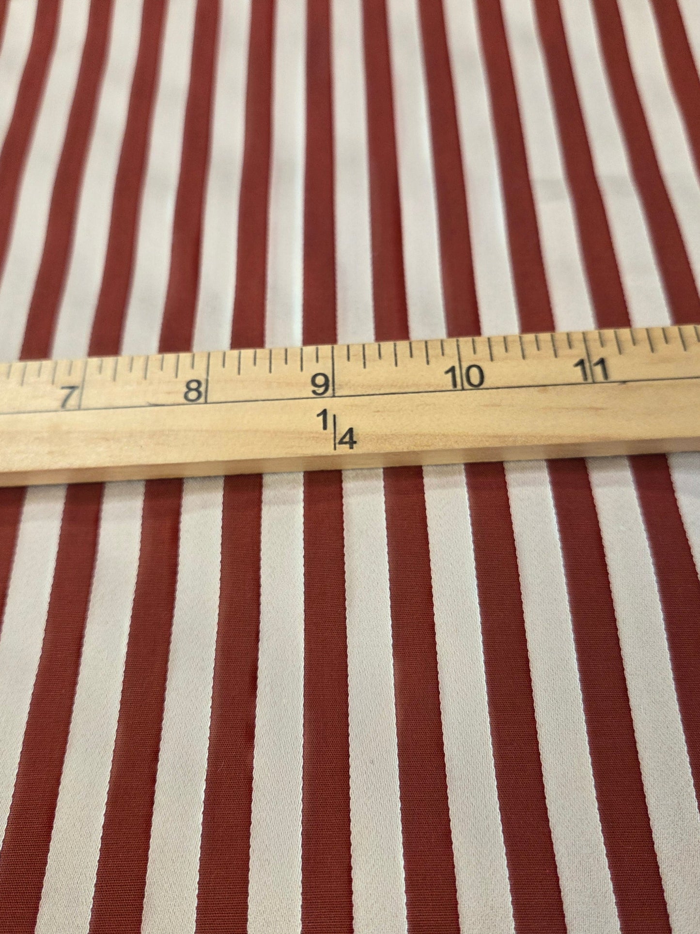Red and white vertically striped fabric with a wooden 12-inch ruler laid horizontally for scale.