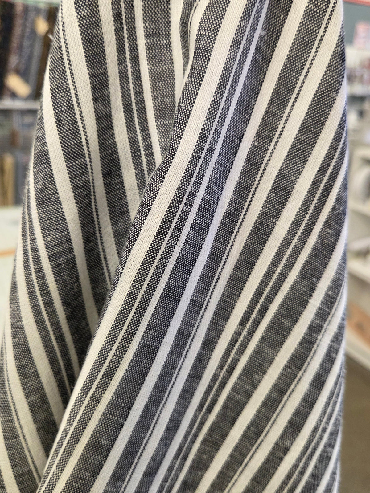 A close-up of a striped fabric, likely a shirt or garment, featuring vertical stripes in black, white, and gray.