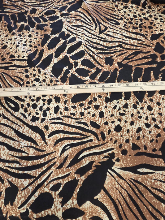 A large piece of fabric with a bold animal print pattern in black, brown, and beige, spread out on a cutting mat with a wooden ruler placed horizontally to show the scale.