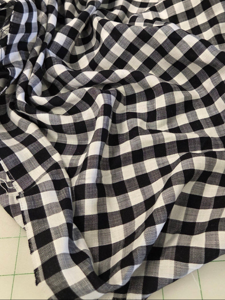 Black and white gingham checkered fabric draped on a green grid cutting mat.