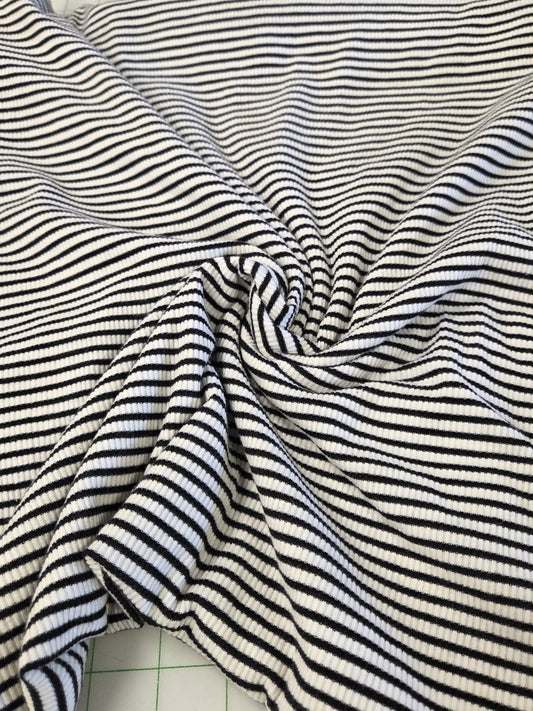 Black and white striped fabric draped in a spiral pattern on a white cutting mat with grid lines.