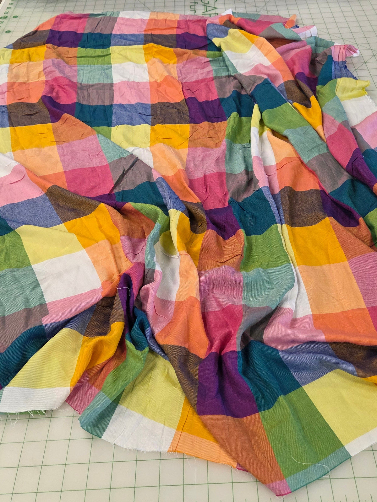 The rayon twill weave fabric features a mix of pink, orange, yellow, green, blue, and purple plaid blocks.
