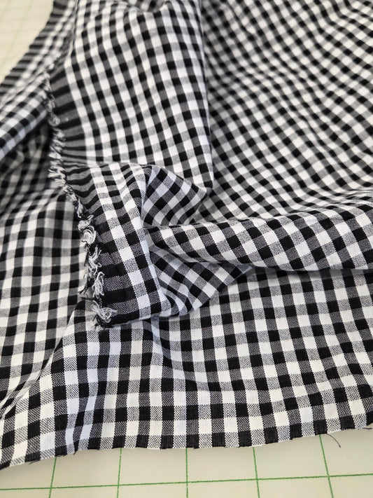 Black and white gingham checkered fabric draped over a green grid cutting mat.