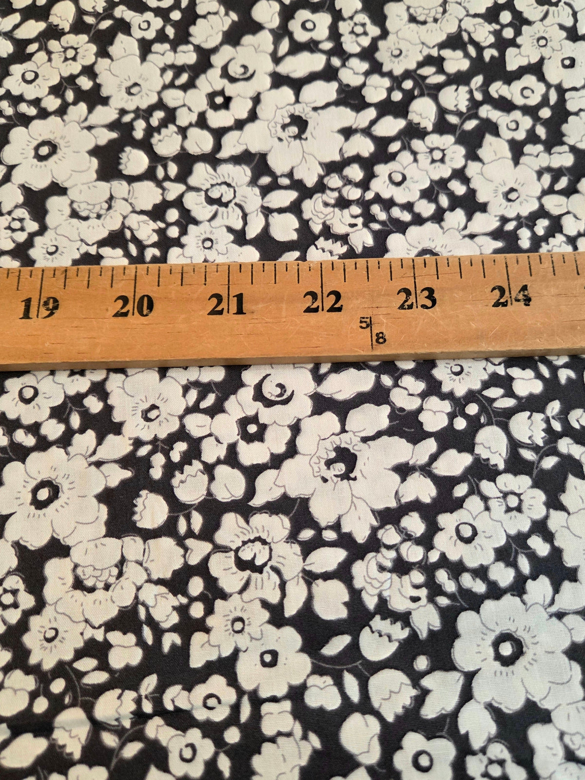 navy and white floral patterned fabric with a wooden ruler laid horizontally to show scale.