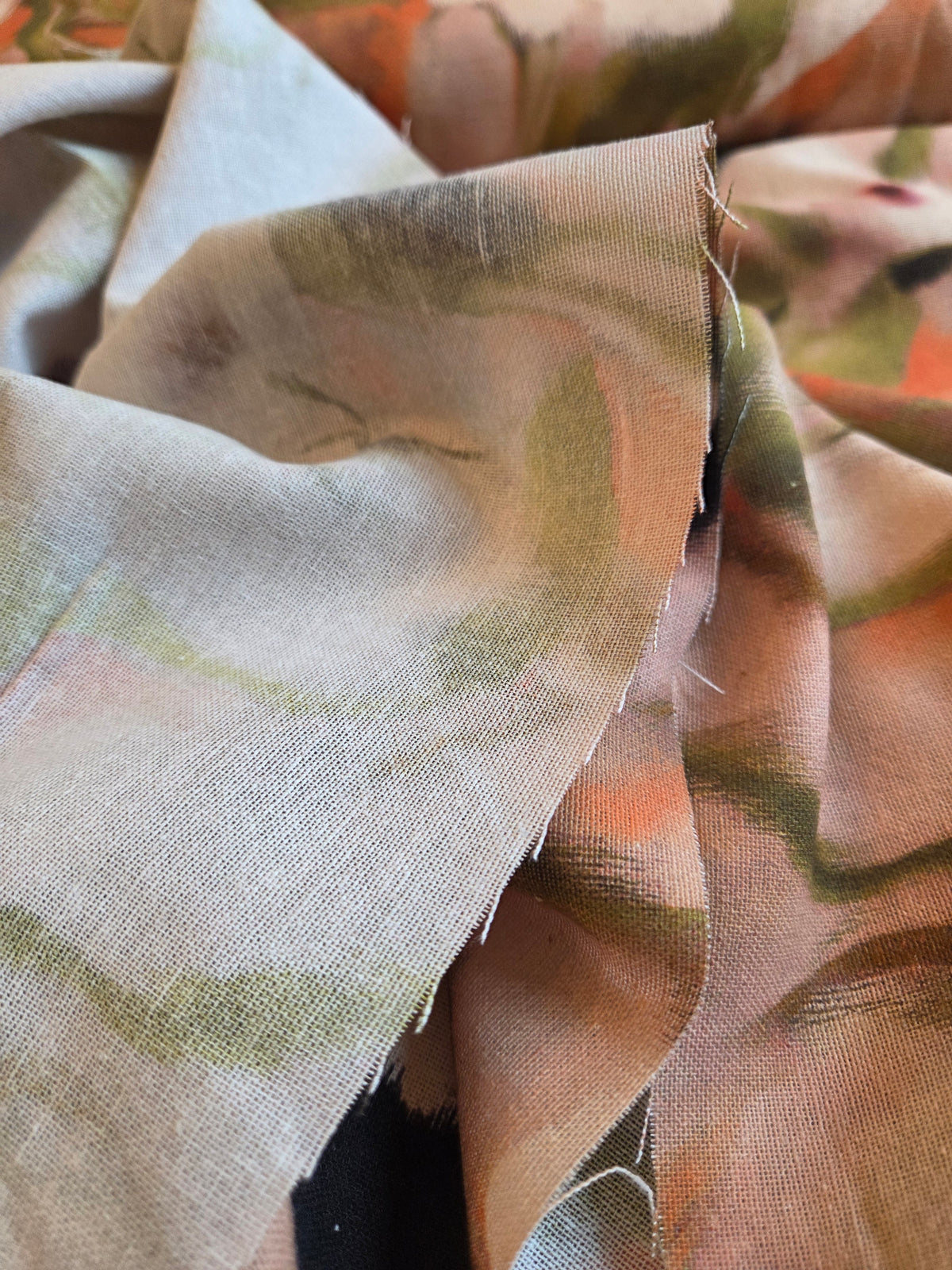 A close-up of draped fabric with a soft abstract print in muted peach, sage green, beige, and brown tones. LA Finch Fabrics Apparel Fabric by the yard
