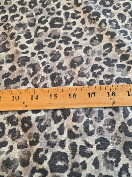 Leopard print fabric with a beige and gray base and black spots, shown with a wooden ruler for scale. LA Finch Fabrics by the yard fabrics available online and  in store