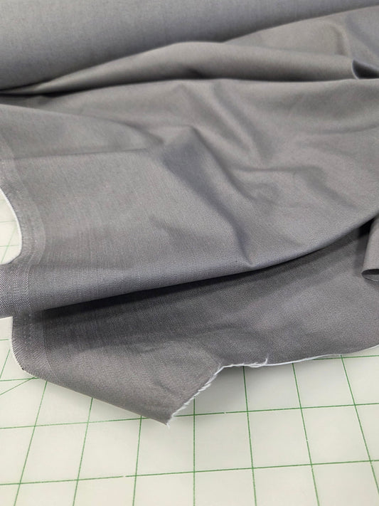 Gray fabric draped over a green-lined cutting mat.