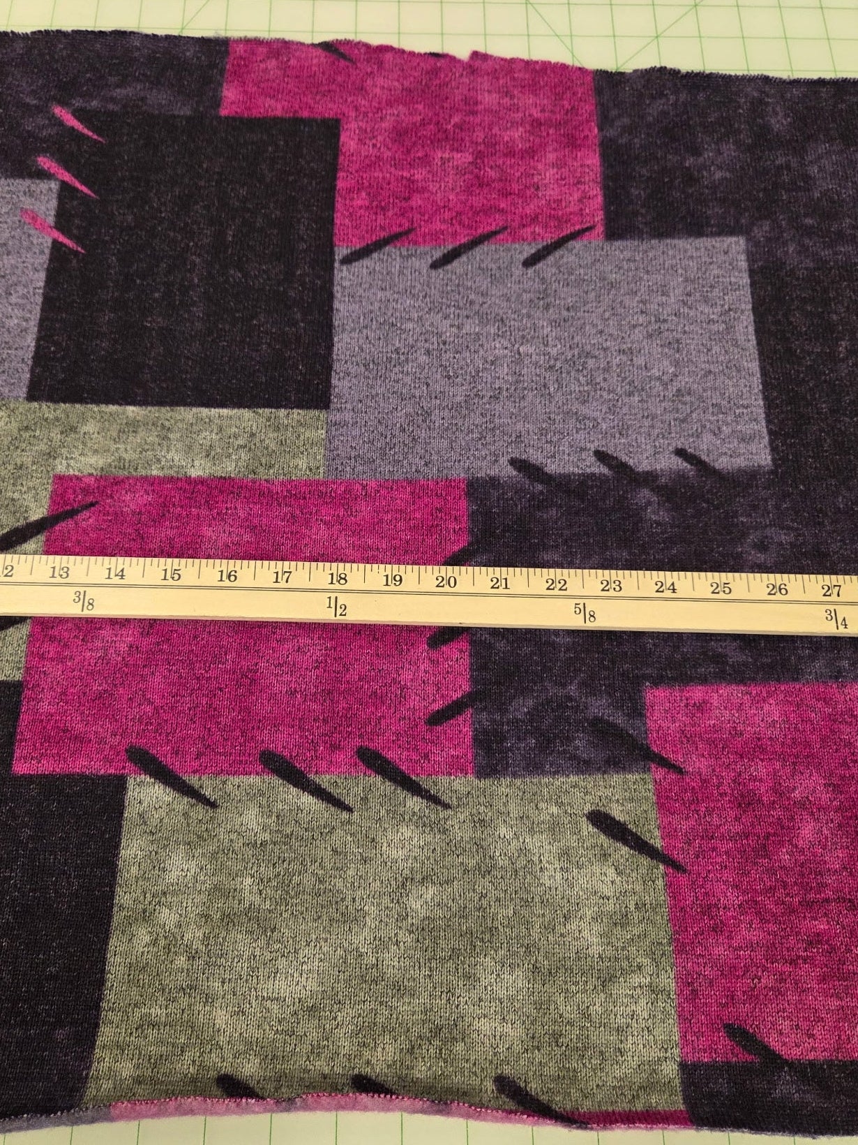 Patchwork fabric with a ruler for scale on a grid background. fabric for making cardigans, joggers, skirts, sweaters.