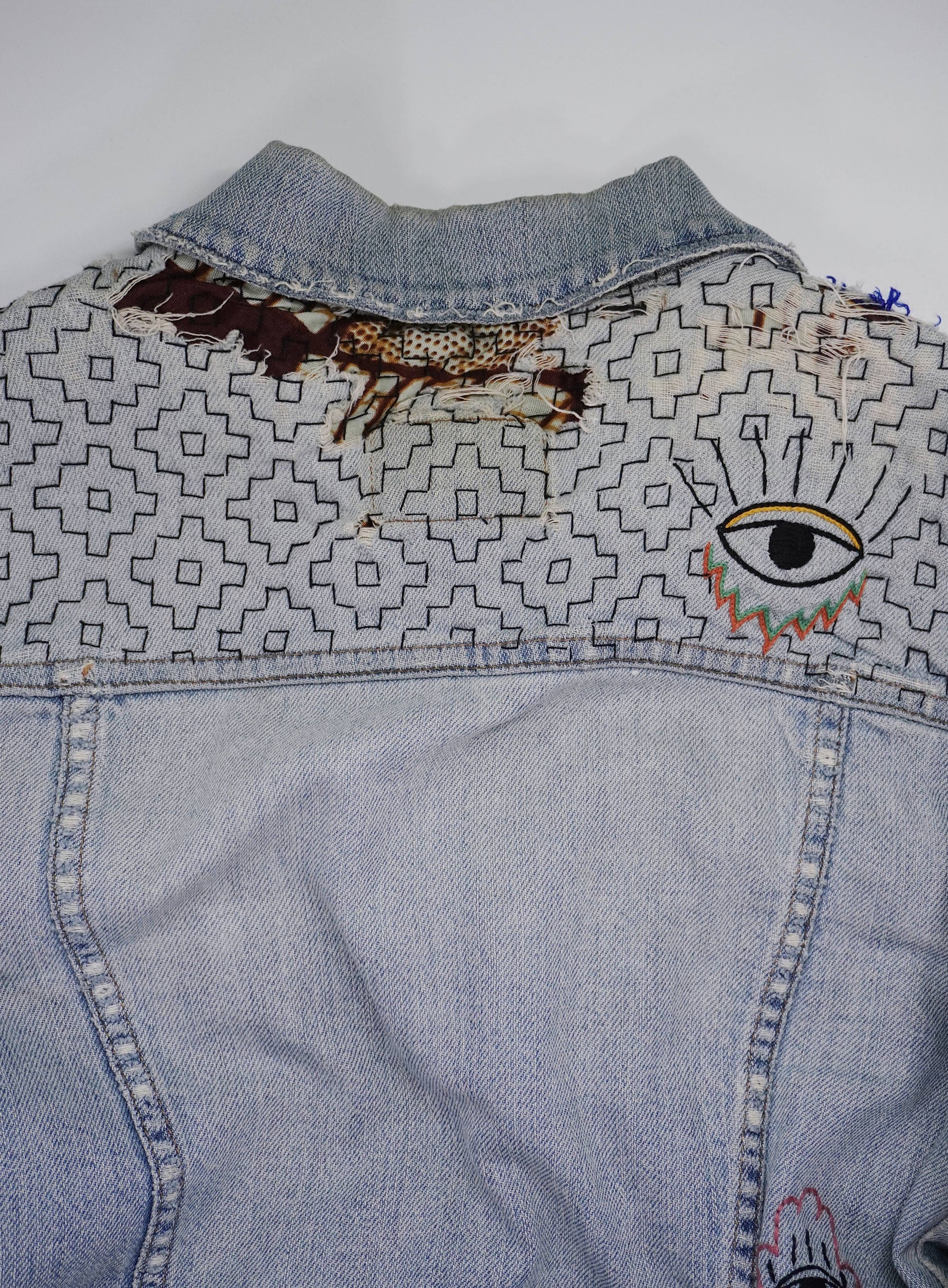 Denim jacket with embroidered designs on a white background