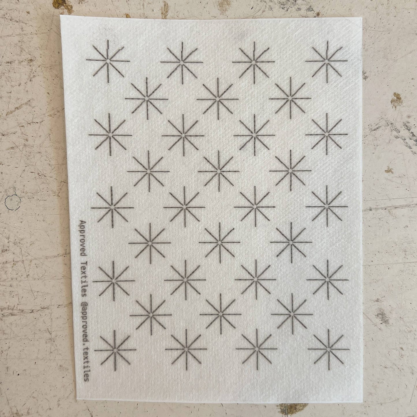 White cloth with black star patterns on a textured beige surface