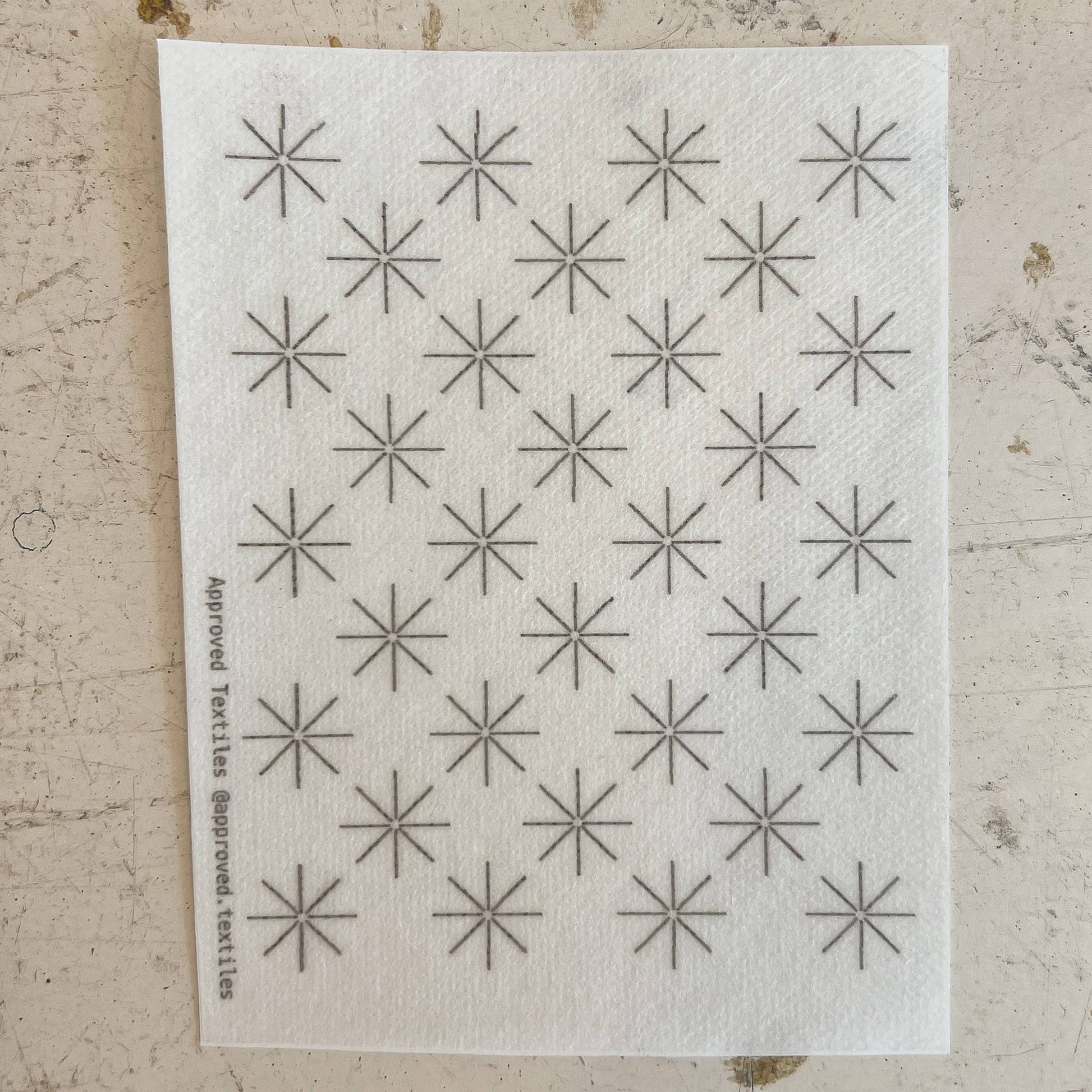 White cloth with black star patterns on a textured beige surface