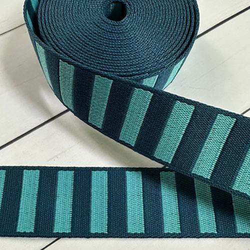 Roll of blue and green striped fabric on a light background