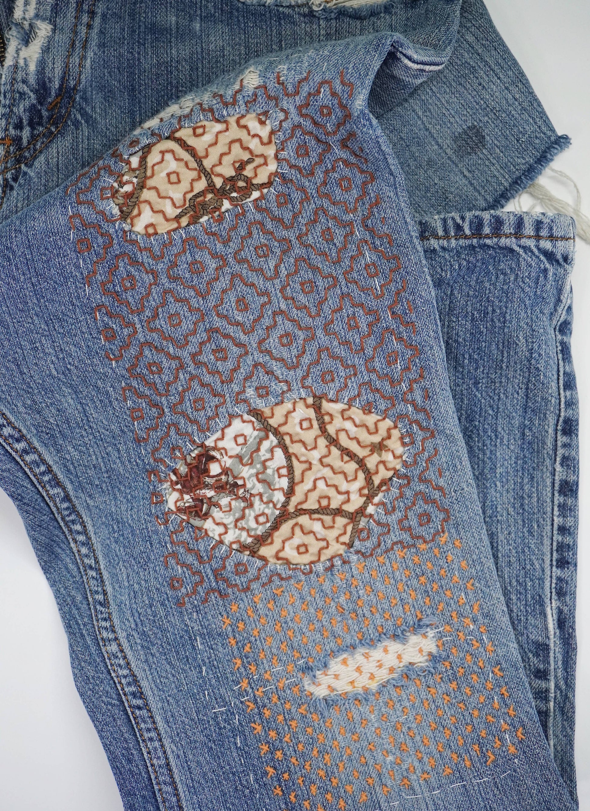 Close-up of blue jeans with butterfly pattern on a white background