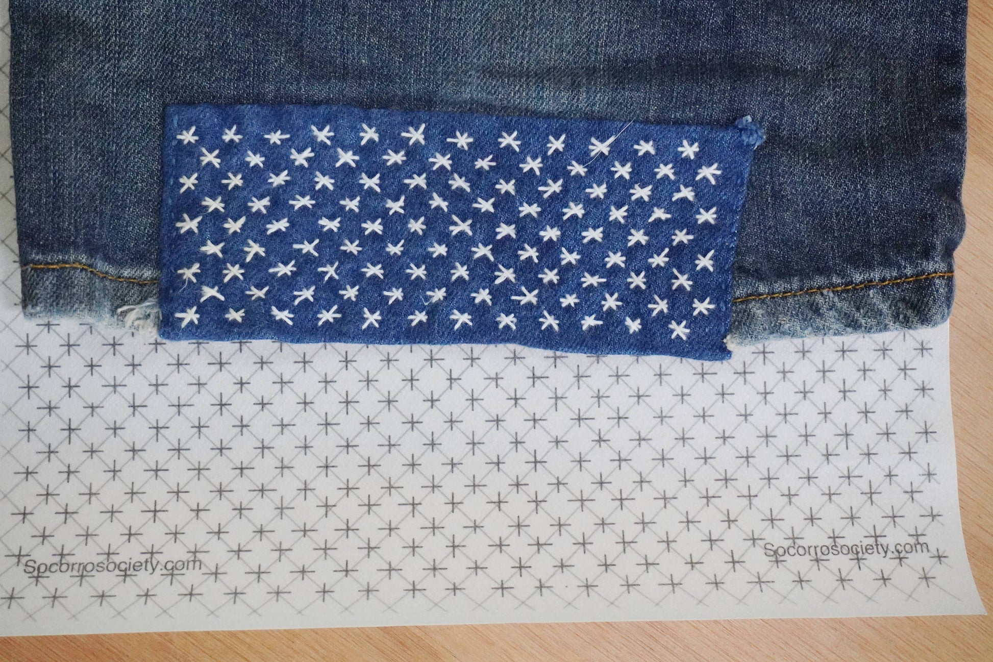 Patch of blue fabric with white star pattern on a denim background