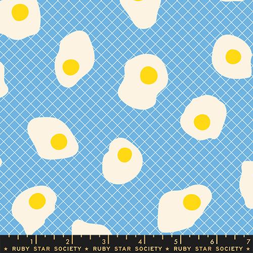 Pattern of white eggs with yellow yolks on a blue grid background, featuring Ruby Star Society label.