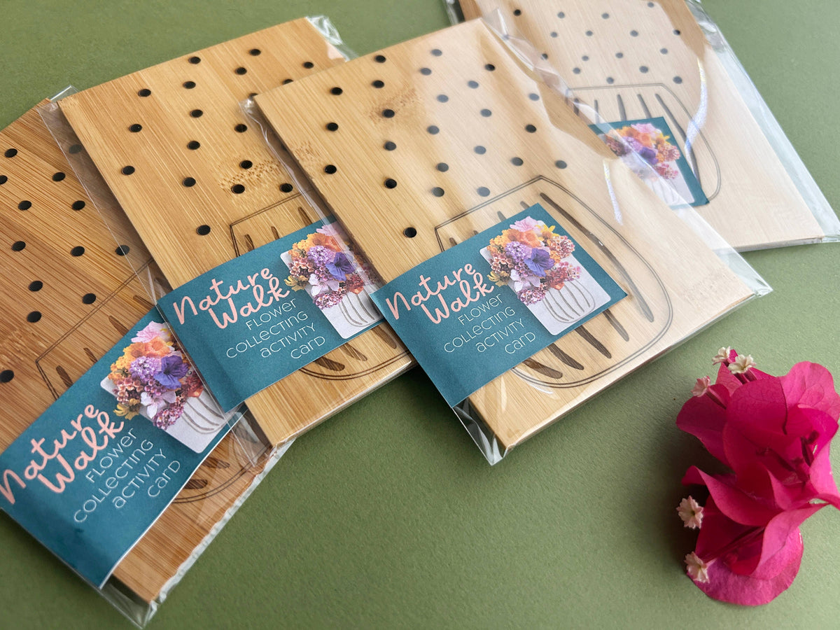 Wooden activity cards with floral designs and 'Nature Walk' labels on a green surface.