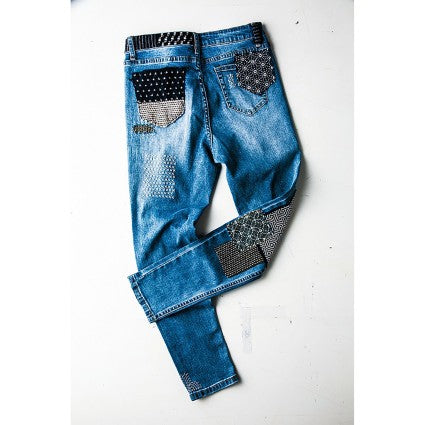 Blue jeans with decorative patches on a white background