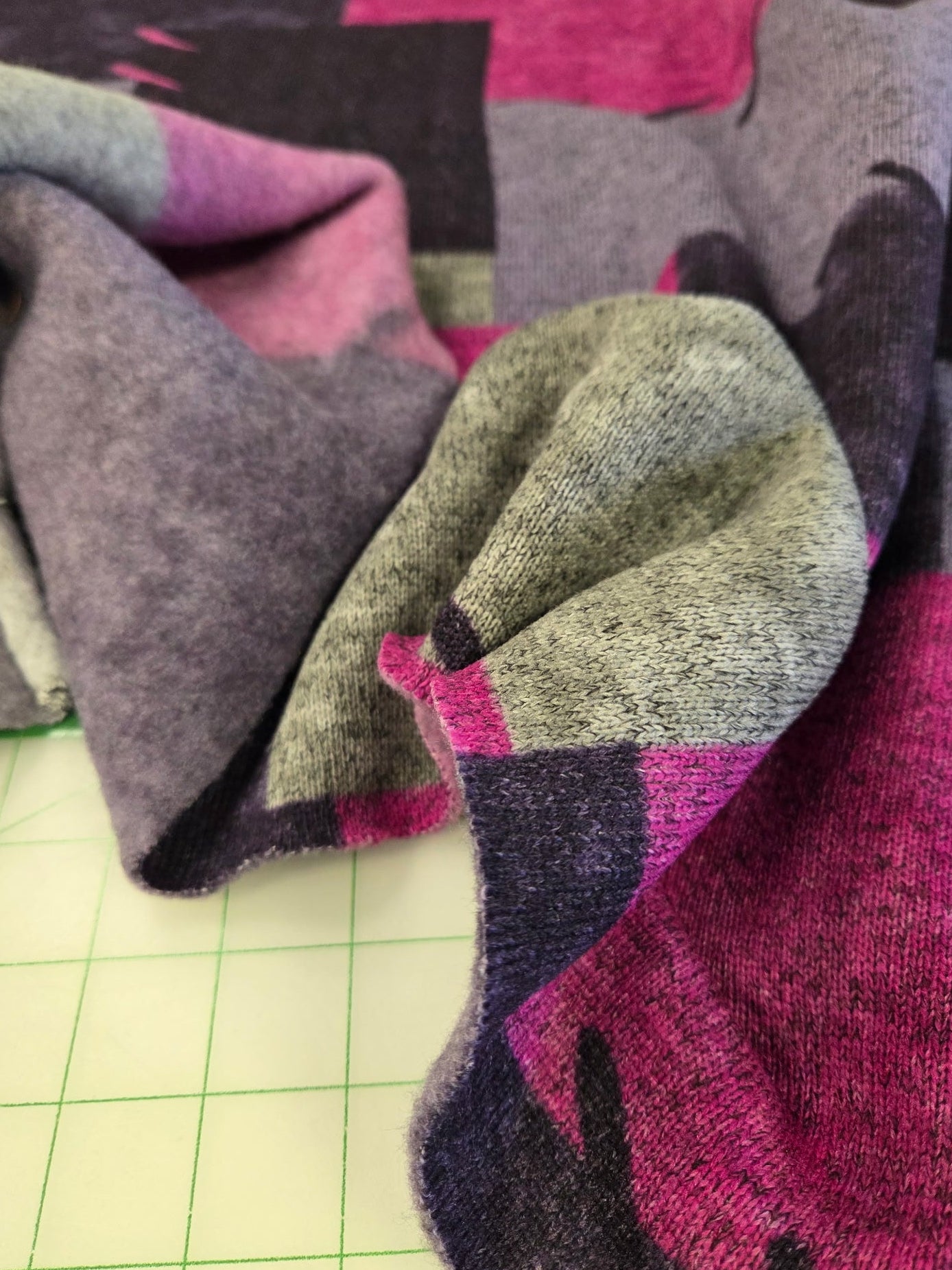 Folded fabric with pink, gray, and black pattern on a grid background
