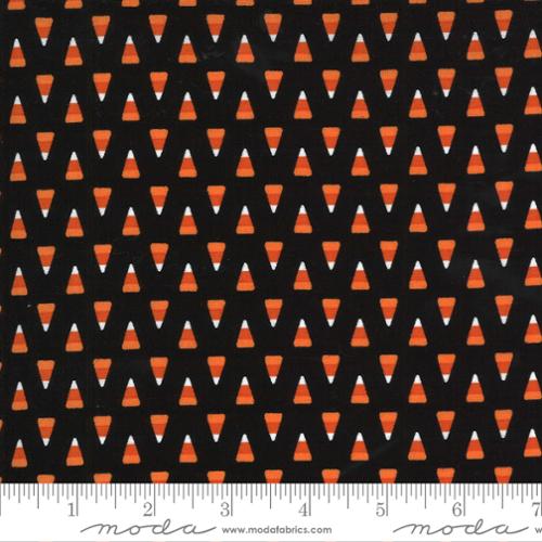 Pattern of orange candy corns on a black background with a ruler at the bottom.